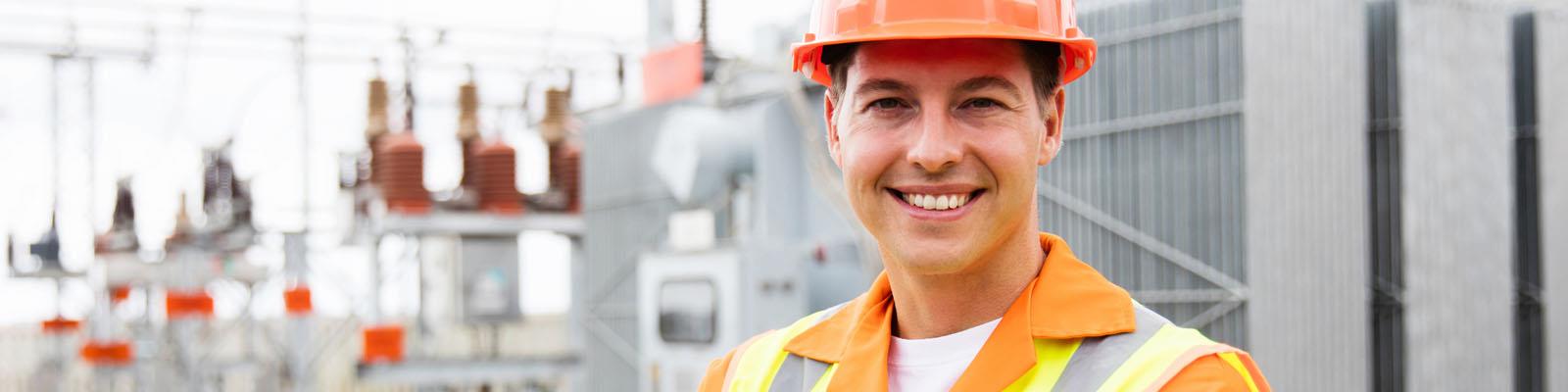 Electrical engineer standing in front of equipment wearing hard hat